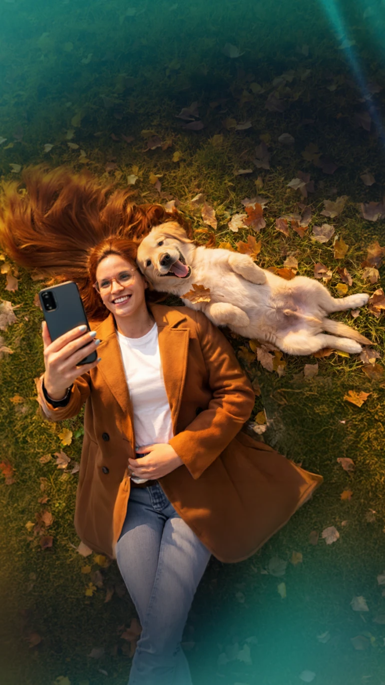 Mujer acostada en el Césped junto a su Golden retriever disfrutando y tomándose una selfie